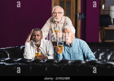 choqué des amis multiethniques seniors avec des verres de bière regardant le championnat de football dans le pub Banque D'Images