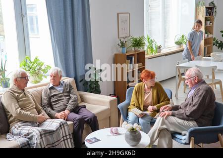Les personnes âgées assis sur un canapé parlent les unes aux autres et se reposent tout en passant du temps dans une maison de soins infirmiers Banque D'Images