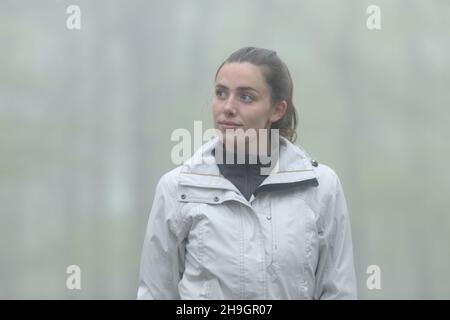 Trekker marchant seul dans une forêt brumeux qui regarde à côté Banque D'Images