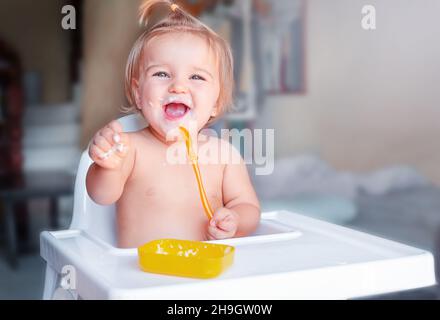 Premier repas de bébé.L'enfant mange seul avec une cuillère Banque D'Images