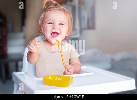 Premier repas de bébé.L'enfant mange seul avec une cuillère Banque D'Images