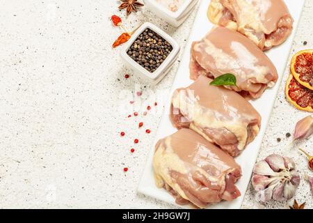 Cuisse de poulet crue sans os ni peau.Un ingrédient utile pour préparer des aliments sains, des épices, de l'ail.Arrière-plan léger, vue de dessus Banque D'Images