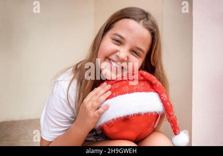 Portrait de Noël de l'enfant avec un ornement de Noël.Fille tenant le jouet de Noël, vêtue dans le chapeau de Santa Banque D'Images