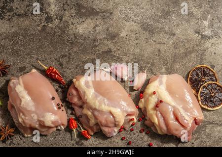 Cuisse de poulet crue sans os ni peau.Un ingrédient utile pour préparer des aliments sains, des épices, de l'ail.Arrière-plan en pierre sombre, vue du dessus Banque D'Images