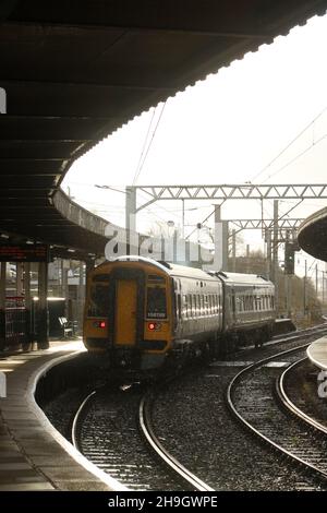 Train à grande unité Northern express sprinter diesel-multiple quittant la gare de Carnforth, plate-forme 1, le 6th décembre 2021, douche à effet pluie et peluches à la lumière du soleil. Banque D'Images