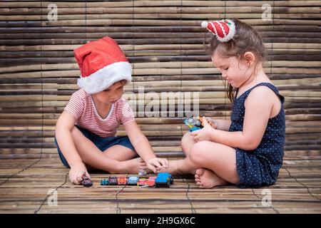 les enfants jouent aux voitures sur fond de bois.Garçon et fille jouant ensemble sur fond de bambou Banque D'Images