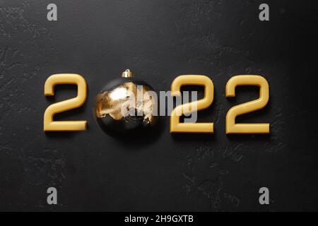 Joyeux nouvel an 2022 nombre d'or avec boule décorée de luxe pot métallique isolé sur fond noir nuit.Concept de vacances.Vue de dessus, espace de copie.