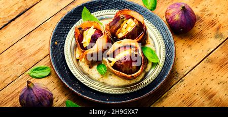 Figues enrobées de bacon rôti farci de fromage de chèvre. Figues cuites au four Banque D'Images