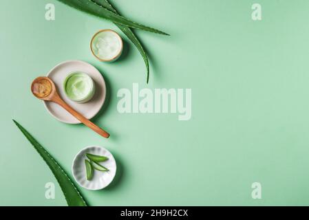 Feuilles et gel d'aloe vera pour le soin de la peau sur vert, vue de dessus, espace de copie.Cosmétiques naturels organiques à base d'aloe vera pour les soins du visage et du corps. Banque D'Images