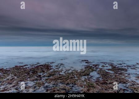 Rochers sur la plage à marée basse baie de compton sur la côte de l'île de wight, rive de l'île de wight sous la lumière bleue au coucher du soleil, paysage marin atmosphérique IOW. Banque D'Images