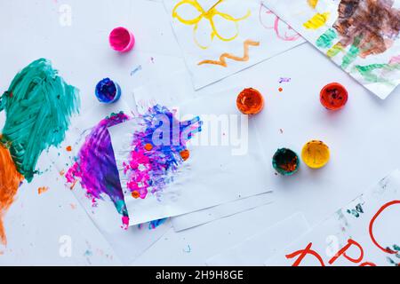 Taches et taches d'aquarelles lumineuses sur papier blanc.Vue de dessus sur les pots et les peintures de couleurs mélangées.Fond lumineux pour les artistes et les designers Banque D'Images