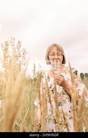 Portrait d'une femme âgée tenant un bouquet de fleurs, sentant l'odeur des pâquerettes.Automne. Banque D'Images