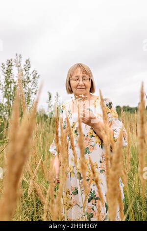 Portrait d'une femme âgée tenant un bouquet de fleurs, sentant l'odeur des pâquerettes.Automne. Banque D'Images