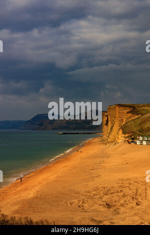 Un puits de lumière solaire d'automne illumine la falaise est de grès instable et dangereuse sur la côte jurassique à Burton Bradstock, Dorset, Angleterre, Royaume-Uni Banque D'Images