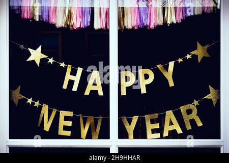 Un personnage de découpe de papier doré du nouvel an heureux avec étoile suspendue est monté sur la fenêtre pendant le festival des fêtes de Noël et du nouvel an.Joyeux N Banque D'Images