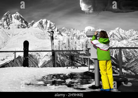 Une fille regarde à travers des jumelles sur le pont d'observation de la station de ski en montagne d'hiver par beau temps.Montagnes du Caucase.Région de Svaneti en Géorgie.Supports Banque D'Images