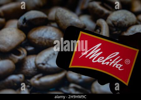 Rheinbach, Allemagne, le 1 octobre 2021, le logo de la marque « Melitta » sur l'écran d'un smartphone devant une photo avec des grains de café rôtis Banque D'Images