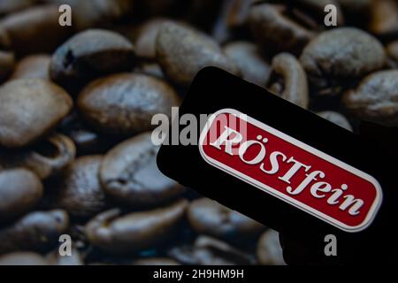 Rheinbach, Allemagne 1 octobre 2021, le logo de la marque 'Röstfein' sur l'écran d'un smartphone devant une photo avec des grains de café rôtis Banque D'Images
