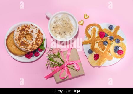 Crêpes Valentines en forme de XOXO, avec une tasse de café et de baies sur fond rose.Idée de petit déjeuner sucré et savoureux pour la Saint-Valentin Banque D'Images