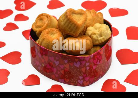 Isoler.Saint Valentin.Boîte dans la forme d'un coeur en elle beaucoup de cupcakes, des biscuits, se trouvent à côté d'un grand nombre de coeurs rouges sculptés.Photographie horizontale Banque D'Images