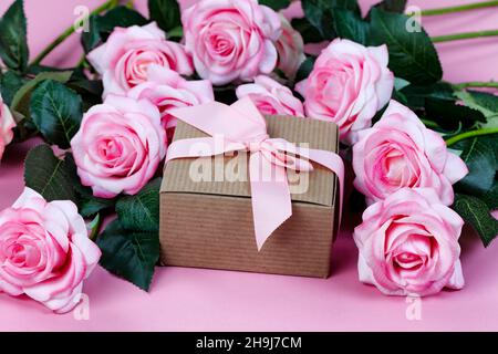 Vue de face de fleurs roses claires et boîte-cadeau formant un fond rose pour le concept de fête des mères ou de vacances de la Saint-Valentin Banque D'Images