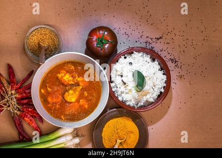 Curry de poulet Madras et riz basmati dans un bol, épices (curcuma, koriander), tomate, piment,oignon sur table brune.Cuisine traditionnelle indienne, Banque D'Images