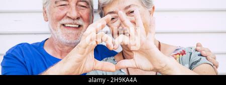 Les personnes âgées aiment le soupir de coeur avec les mains dans la composition d'en-tête de bannière.Un vieil homme et une femme heureux sourient en arrière-plan Banque D'Images