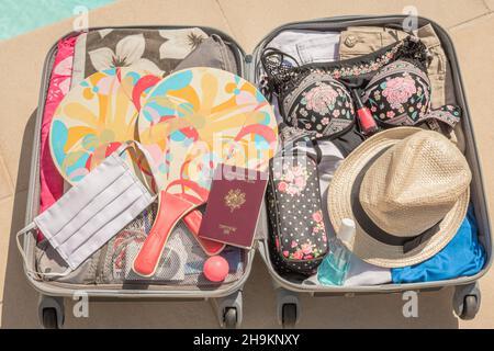 Valise à roulettes avec masque de protection du visage et gel hydroalcoolique pour lutter contre le virus Covid-19, le coronavirus, l'allergie, l'épidémie et la pandémie. Banque D'Images