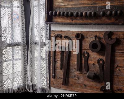 Panneau en bois avec anciens outils devant une fenêtre avec rideau. Banque D'Images