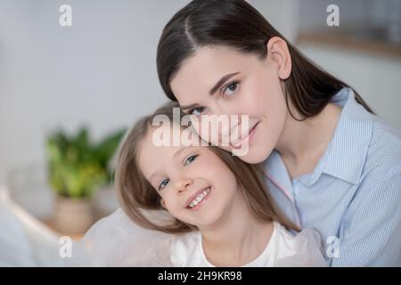 Une mère heureuse et sa fille joyeuse posant pour l'appareil photo Banque D'Images