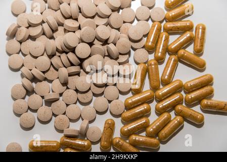 Capsules transparentes avec poudre jaune et pilules marron clair sur fond blanc vue rapprochée du dessus Banque D'Images