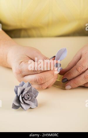 Le maître sculpte un pétale à partir d'argile polymère pour créer une fleur décorative. Banque D'Images