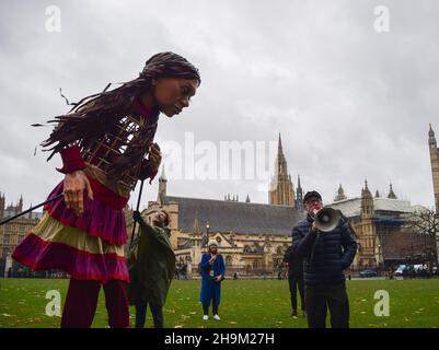 Londres, Royaume-Uni.07ème décembre 2021.Little Amal se trouve à côté du député travailliste Jeremy Corbyn alors qu'il s'adresse aux manifestants à travers un mégaphone pendant la manifestation.les manifestants se sont rassemblés sur la place du Parlement avec la marionnette Little Amal, représentant un enfant réfugié syrien, en soutien aux réfugiés et en protestation contre le projet de loi sur la nationalité et les frontières,qui a été débattu par le gouvernement.Crédit : SOPA Images Limited/Alamy Live News Banque D'Images