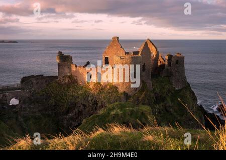 Les ruines emblématiques du château de Dunluce perchées sur un éperon rocheux de la côte nord d'Antrim en Irlande du Nord. Banque D'Images