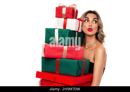 Jeune femme émerveillée avec une pile de cadeaux du nouvel an, excitée femme en tenue de fête tient des cadeaux de Noël Banque D'Images