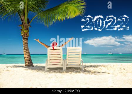 nouveau concept de l'année 2022 avec femme au chapeau du père noël se détendant sur la plage tropicale.Vacances du nouvel an sur l'île. Banque D'Images