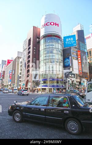 Le bâtiment Ricoh et d'autres bâtiments colorés au coeur de Ginza, Tokyo, Japon avec des taxis et d'autres véhicules à la célèbre traversée de Ginza. Banque D'Images