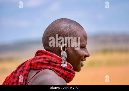 Maasai Mara, Kenya - 25 septembre 2013.Vue rapprochée d'une boucle d'oreille percée et d'un tissu rouge traditionnel porté par un membre mâle de la tribu Masai. Banque D'Images