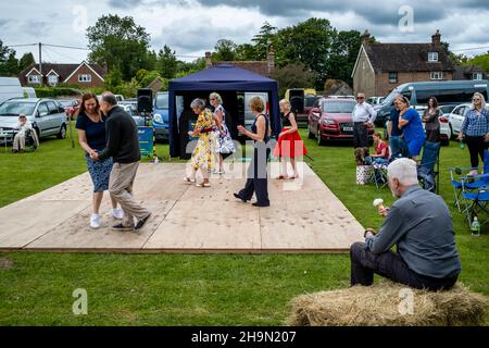 Un homme mange une glace tout en observant les habitants de la région dansant au Nutley Village Fete, Nutley, East Sussex, Royaume-Uni. Banque D'Images