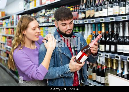 Positif homme et femme choisissant une bouteille de cava Banque D'Images