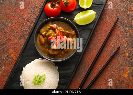 Bol avec savoureux curry de bœuf et riz sur fond de couleur Banque D'Images