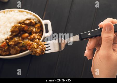 Femme mangeant du curry de bœuf savoureux à partir d'un plat sur la table Banque D'Images