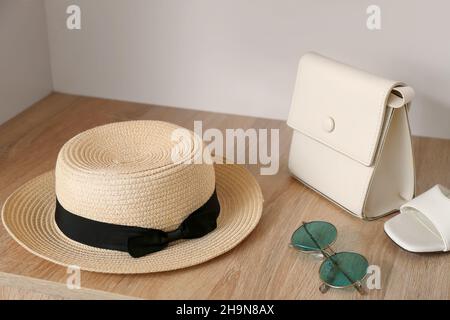 Chapeau de paille élégant avec lunettes de soleil et sac sur étagère dans l'armoire Banque D'Images