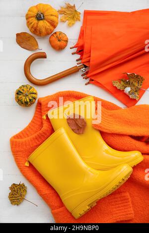 Parapluie, bottes en caoutchouc, chandail et citrouilles sur fond en bois clair, gros plan Banque D'Images