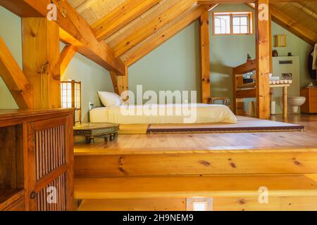 Très grand matelas posé sur le dessus de tatami tapis dans le concept ouvert chambre principale avec plancher en bois de pin à l'intérieur de la maison de cadre en bois. Banque D'Images