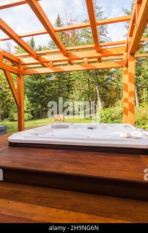 Pergola avec cadre en bois de pin blanc huilé et spa sur plate-forme en bois levé dans l'arrière-cour. Banque D'Images