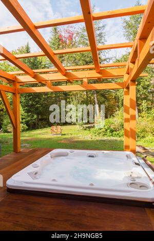 Pergola avec cadre en bois de pin blanc huilé et spa sur plate-forme en bois levé dans l'arrière-cour. Banque D'Images