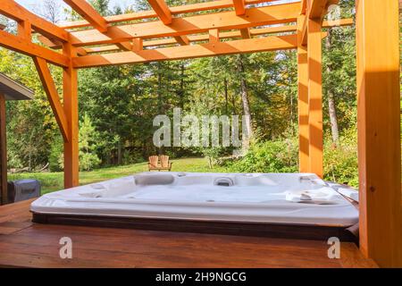 Pergola avec cadre en bois de pin blanc huilé et spa sur plate-forme en bois levé dans l'arrière-cour. Banque D'Images