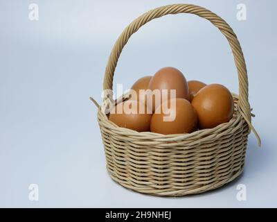 œufs dans un panier en bambou sur fond blanc Banque D'Images