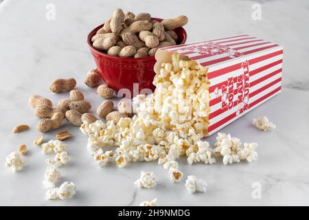 Gros plan d'un contenant de pop-corn avec un bol d'arachides à l'arrière. Banque D'Images